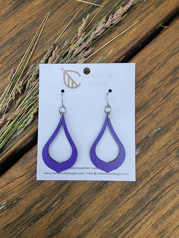 a wooden purple pair of earrings in the shape of a cut out tear drop. hypoallergenic silver hooks.