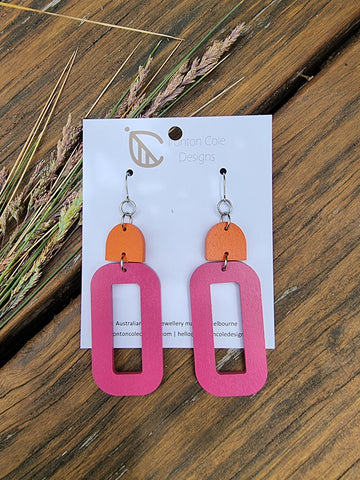 Hot pink oval wooden earrings paired with an orange arch top. Silver hypoallergenic hooks.