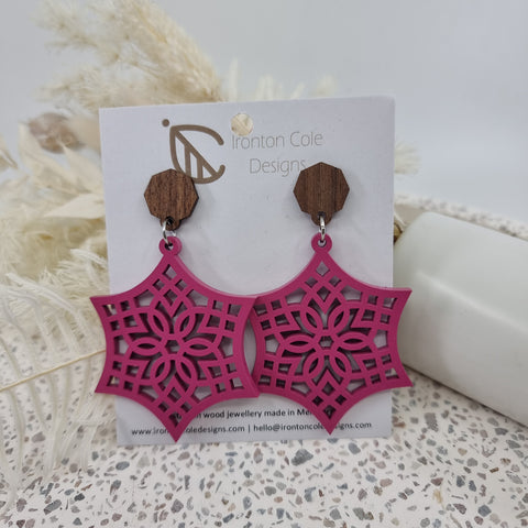 A stunning pink coloured wooden earring in the shape of a star  with celtic patterns. 