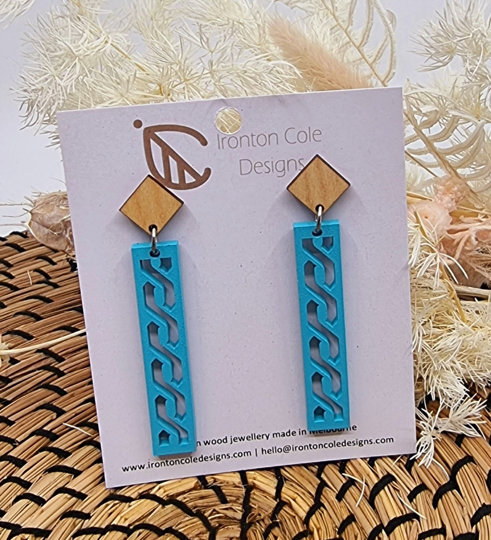 Baby blue painted wooden earrings in a shape of a bar with an s design.