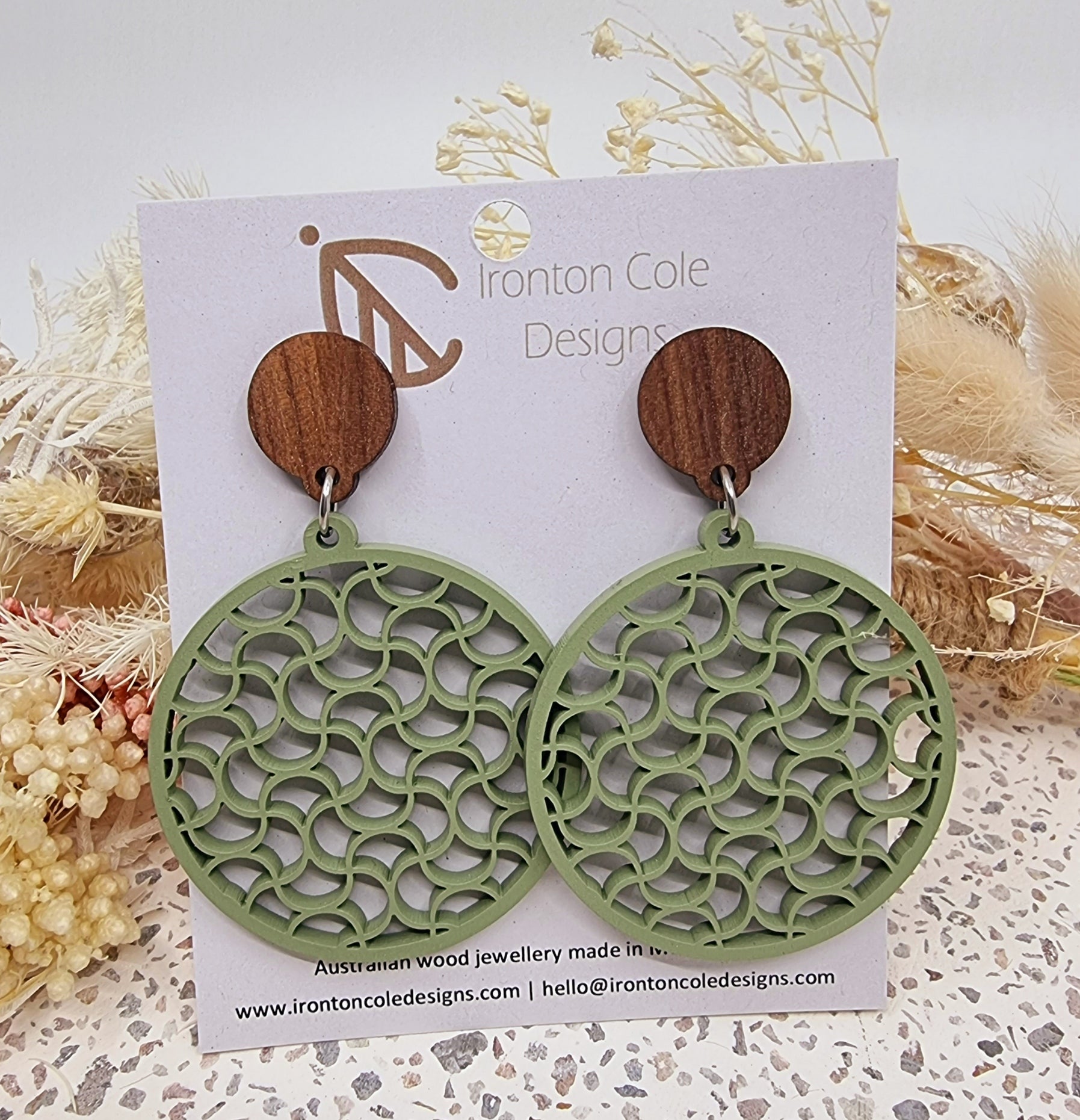 Eucalyptus painted round wooden earrings with a wavy pattern.